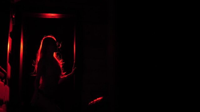 Slender girl in red light waving her hair.