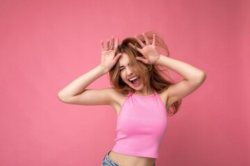 Fototapeta premium Crazy young attractive blonde woman with sincere emotions isolated on background wall with copy space wearing stylish pink top. Positive concept