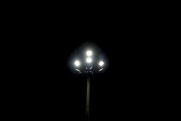 halogen lamp glowing on pole in empty ground at night