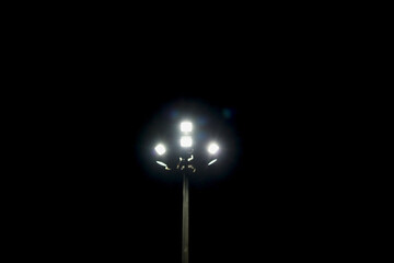 halogen lamp glowing on pole in empty ground at night