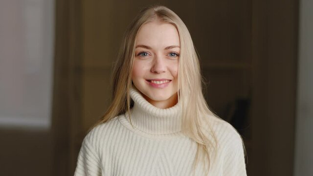 Portrait of successful beautiful caucasian millennial girl wearing white sweater, posing looking at camera, waving her head positively, answering yes. Close-up blonde woman nods approvingly, smiling