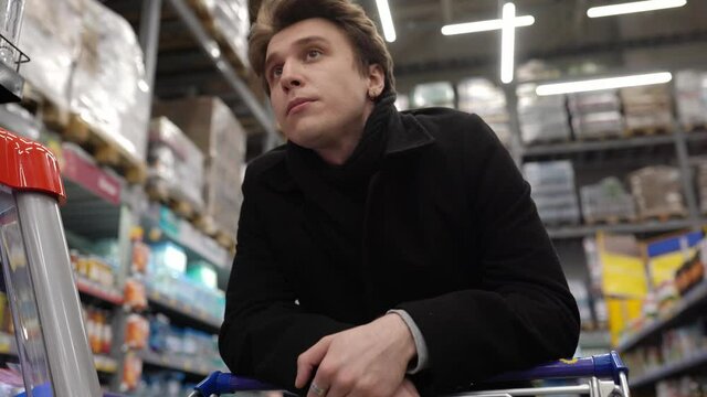 An angry man is standing in line at a supermarket with a cart