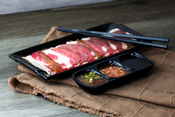 fresh raw pork, meat ,beef, belly, sliced on square plate  on fabric and wood, wooden background, shabu, hot pot ingredients.