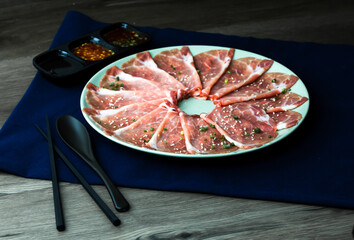 fresh raw pork, meat ,beef, belly, sliced on square dish disk plate  on fabric and wood, wooden background, shabu, hot pot ingredients.