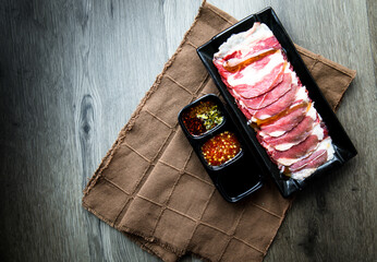 fresh raw pork, meat ,beef, belly, sliced on square plate  on fabric and wood, wooden background, shabu, hot pot ingredients.