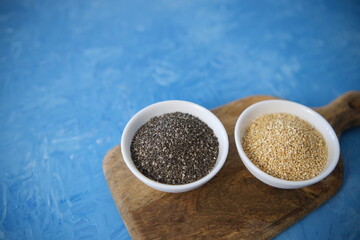 Quinoa and chia seeds are organic food for a healthy diet. In a round bowl. Two white cups. The blue texture is painted with blue oil paints