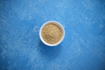 Quinoa is an organic food for healthy eating. In a round bowl. The blue background is painted with oil paints.