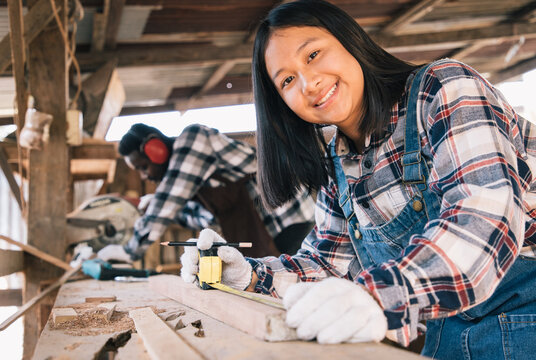 Carpenter woman using tools for wood of his own housing with assistant at work site. Carpenter makes facade details for construction. housekeeping maintenance concept.