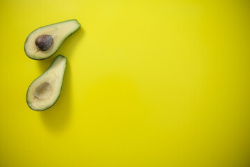 Food background with fresh organic avocado on yellow background. top view, two halves