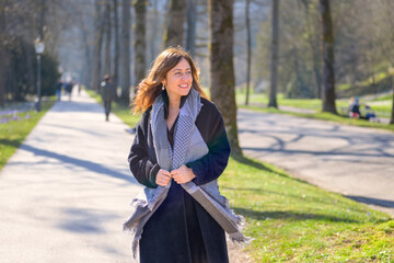 Woman smiling to herself as she strolls through a spring park © michaelheim