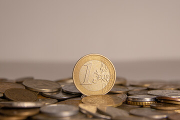 A coin worth one euro stands on other coins.
Photo of one euro coin on a white background.