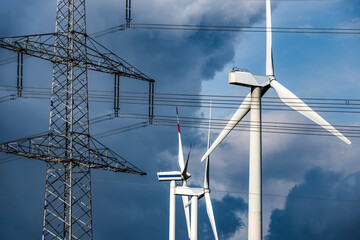 Windräder und Kabeltrosse einer Überlandleitung am Hochspannungsmast 
