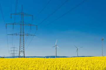 Windräder und Kabeltrosse einer Überlandleitung am Hochspannungsmast 
