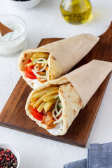 Greek dish gyros with chicken, french fries, tomatoes, onions and pita. Greek cuisine.