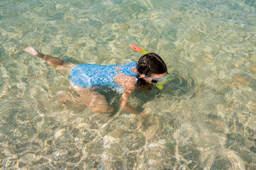 Close up of toddler girl learning snorkeling on shallows. Child immersing the head in water. Kids...