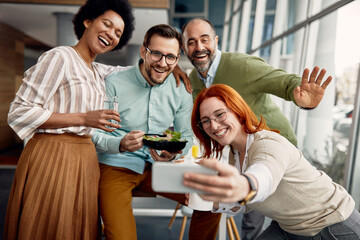 Multi-ethnic group of business co-workers taking selfie and having fun on lunch break in the office.