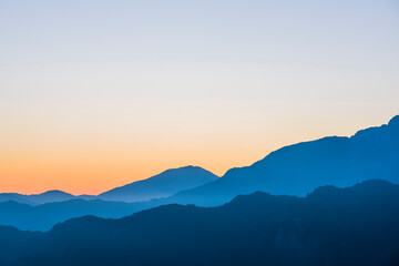 Layers of magnificent mountains with colorful clouds background at sunrise view
