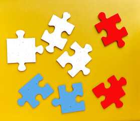 Colored pieces of a puzzle game on yellow background. Studio shot
