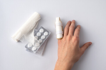 medical splint on a broken finger and medication, on a white background. Medical assistance in case...