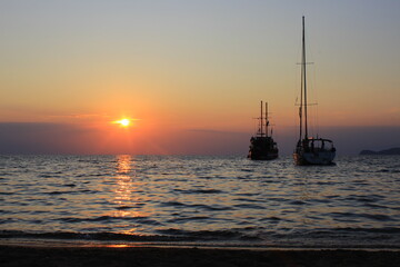 sunset at sea with silhouettes of boats in the background