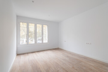 Empty dusted room after renovation with white walls, windows and wooden floor.