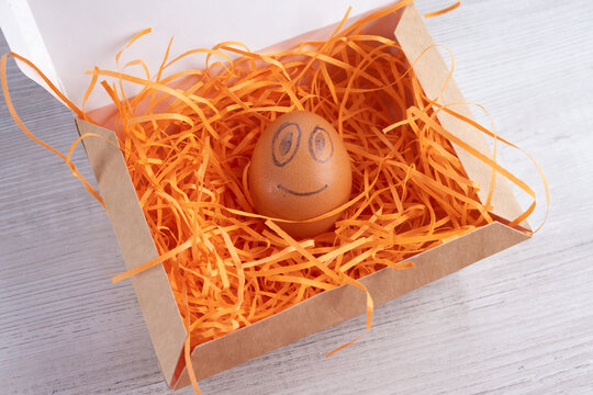 Smiling egg in a cardboard box.