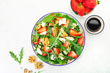 Summer Strawberry Salad. Spinach leaves, arugula, walnuts, blue cheese on gray background. Healthy food concept. Flat lay, top view