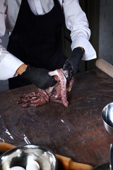 Cook puts a fresh octopus on the table.Cooking octopus. A whole octopus. Seafood dishes. Protein food.An unrecognizable person.Vertical photo.