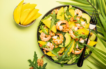 Mango, Shrimps and Avocado Salad with Walnut, Spinach and Arugula. Healthy Eating food concept Top view, lime green background