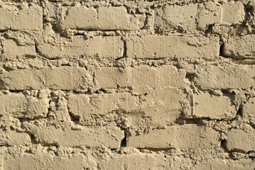 Textured rough wall of yellow bricks outside. Uneven masonry
