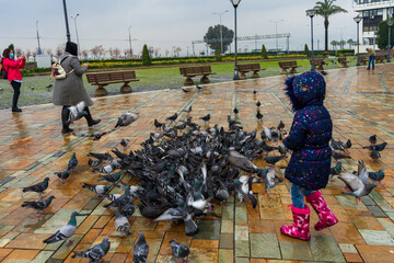 Izmir Turkey; Children play with pigeons in Konak Square, street photography. 20 March 2021