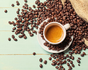 White cup of coffee  and coffee bean on green background. Copy space. Top view.