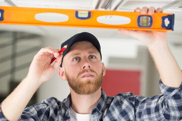 professional construction worker measuring ceiling