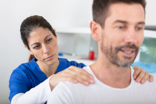 young attractive female doctor making neck massage to male patient