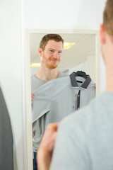 young man trying on clothes in clothing store