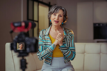 Stylish senior woman making video content using camera