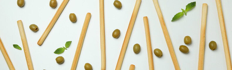 Grissini, olives and basil on white background