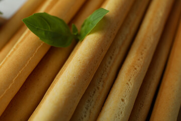 Grissini breadsticks with basil on whole background, close up