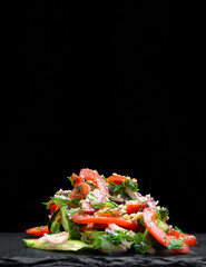Fresh mixed salad with endive and cherry tomatoes on black plate dining, pouring olive oil