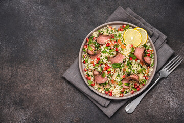 Tabbouleh salad with couscous and chopped beef steak on top. Traditional Middle Eastern cuisine 
