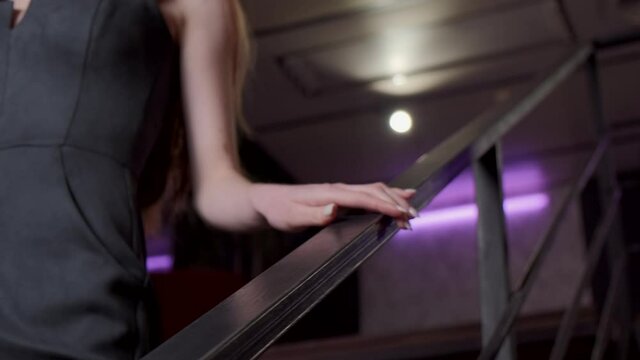 Caucasian woman wearing a black dress is going downstairs to a date