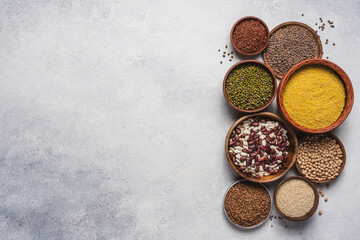 Gluten free cereals and legumes in bowls on white stone background. Buckwheat, millet, quinoa, mung bean peas, lentils, chickpeas, red rice. Healthy food for gluten or vegan intolerances