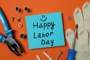 Concept of Happy Labor Day with different accessories on orange background