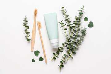 Bamboo toothbrushes and tube of toothpaste on white background. Eucalyptus branches. Natural dental...