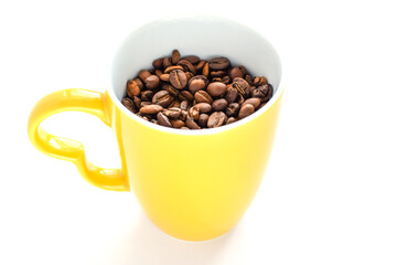 Yellow ceramic cup filled with roasted coffee beans isolated on white background, side view. Copy space for text. Selective focus.