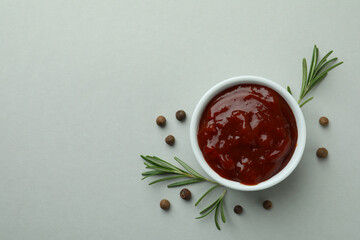 Bowl of barbecue sauce and spices on light gray background