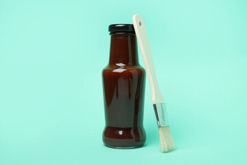 Bottle of barbecue sauce and brush on mint background