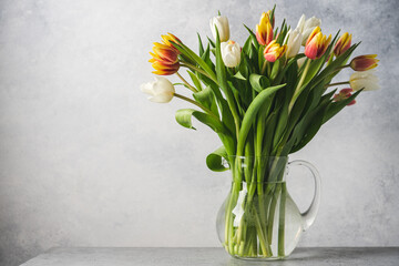 Bouquet of tulips in glass jur on gray background. Easter and spring greeting card