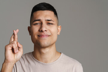 Brunette pleased man holding fingers crossed for good luck