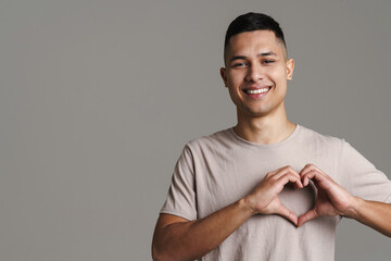 Brunette happy man smiling and showing heart gesture